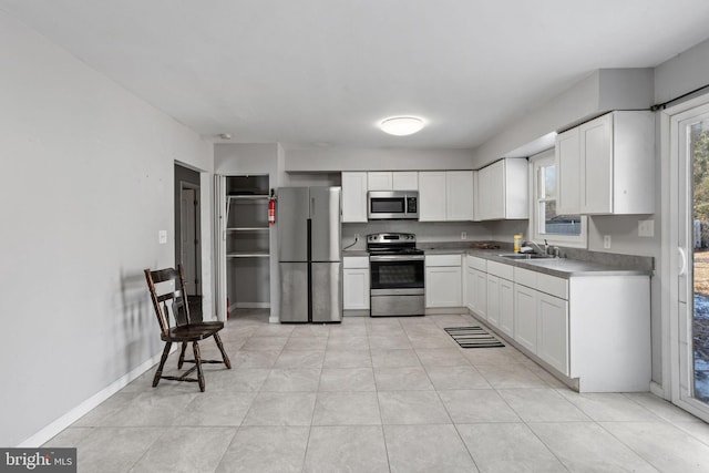 kitchen with light tile patterned floors, appliances with stainless steel finishes, sink, and white cabinetry