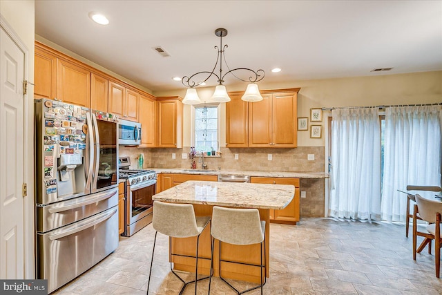 kitchen featuring appliances with stainless steel finishes, a center island, hanging light fixtures, light stone countertops, and sink