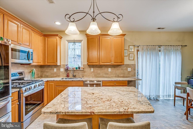 kitchen with a center island, sink, hanging light fixtures, a kitchen breakfast bar, and stainless steel appliances