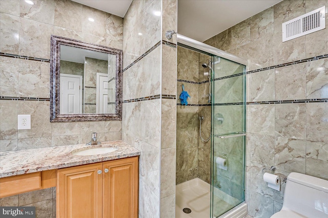 bathroom featuring toilet, vanity, tile walls, and walk in shower