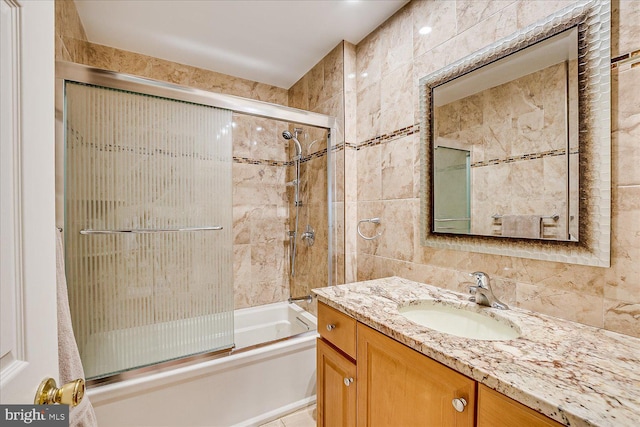 bathroom with enclosed tub / shower combo, tile walls, and vanity