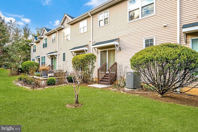 view of front of house with central AC unit and a front lawn