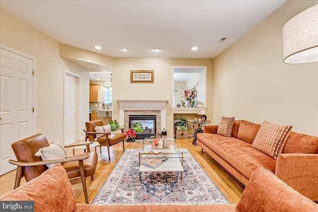 living room with light wood-type flooring and a high end fireplace