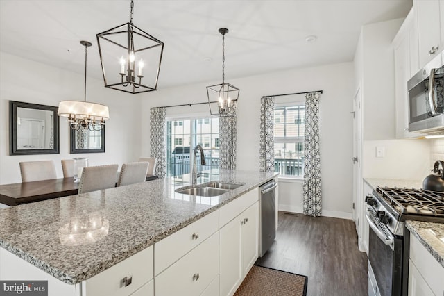 kitchen featuring a kitchen island with sink, white cabinetry, pendant lighting, and appliances with stainless steel finishes