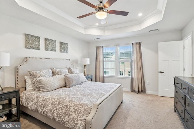 carpeted bedroom with ceiling fan and a tray ceiling