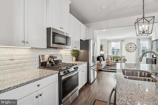 kitchen with white cabinetry, stainless steel appliances, sink, and light stone counters