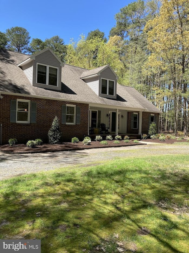 cape cod home featuring a front yard and a porch