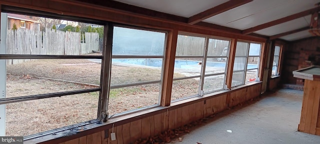 unfurnished sunroom featuring beamed ceiling