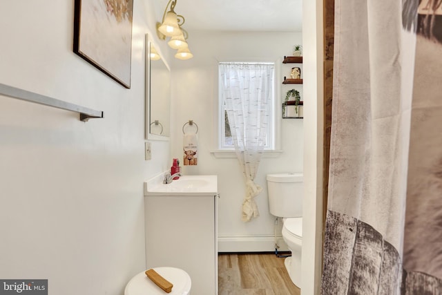 bathroom with toilet, vanity, wood-type flooring, and a baseboard radiator