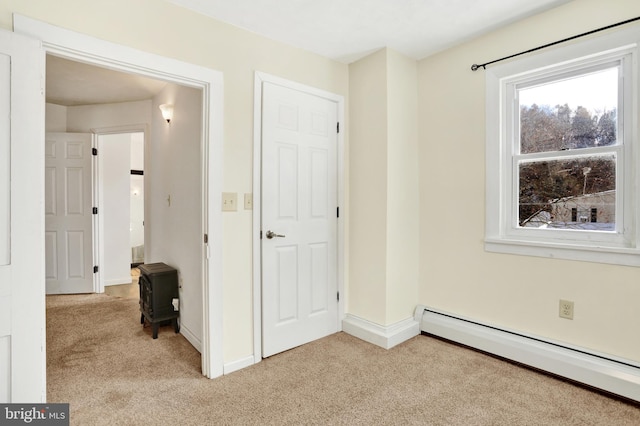 unfurnished bedroom featuring light colored carpet and a baseboard heating unit