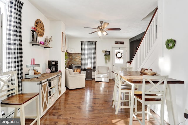 dining area featuring a baseboard heating unit, ceiling fan, and dark hardwood / wood-style flooring