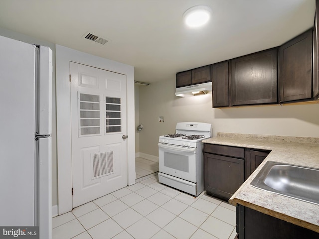 kitchen with sink, white appliances, dark brown cabinetry, and light tile patterned flooring