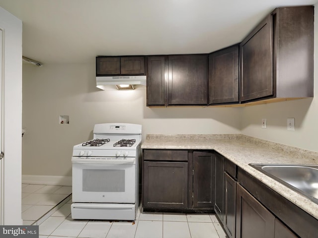 kitchen with gas range gas stove, dark brown cabinets, sink, and light tile patterned floors