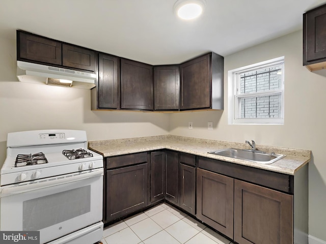 kitchen featuring light tile patterned floors, sink, dark brown cabinetry, and gas range gas stove