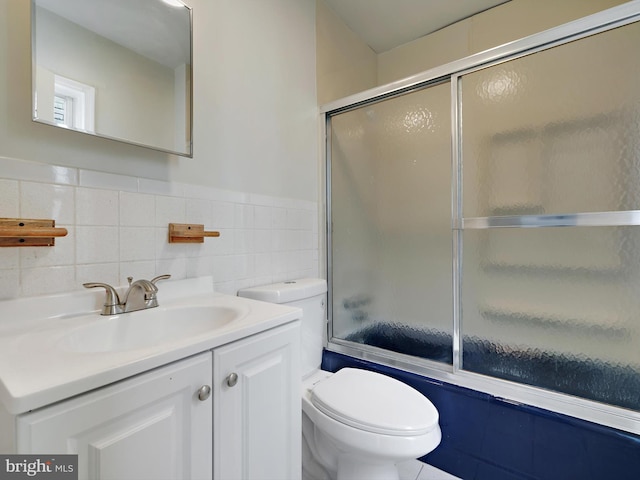 full bathroom with toilet, enclosed tub / shower combo, tile walls, and vanity