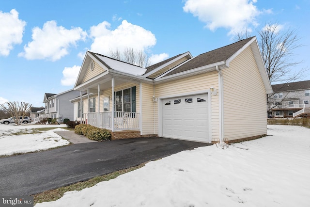 snow covered property featuring covered porch and a garage