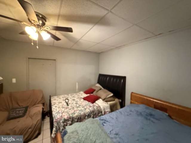 tiled bedroom featuring a drop ceiling and ceiling fan