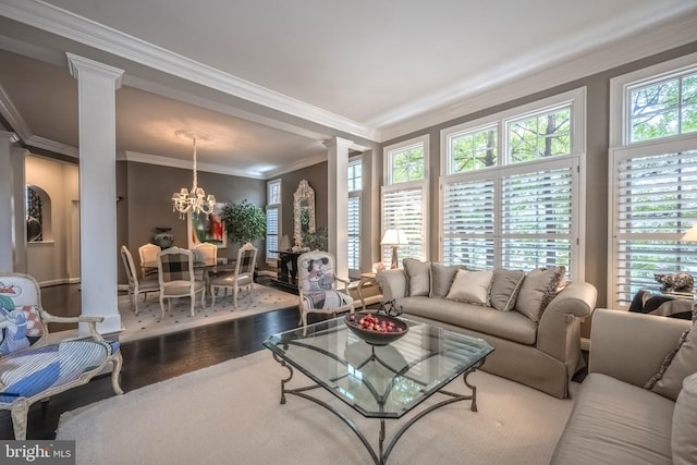 living room featuring ornate columns, ornamental molding, hardwood / wood-style floors, and a notable chandelier