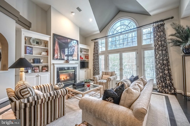 living room with a high end fireplace and high vaulted ceiling