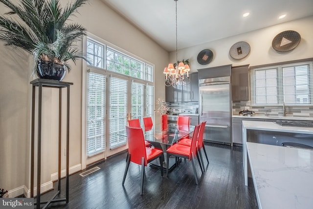 dining area with dark wood-type flooring and a notable chandelier