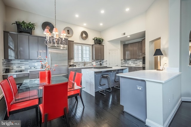 kitchen featuring appliances with stainless steel finishes, tasteful backsplash, a kitchen island, dark hardwood / wood-style flooring, and decorative light fixtures