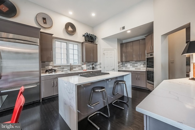 kitchen with a kitchen island, sink, backsplash, dark brown cabinetry, and stainless steel appliances