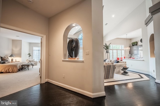 hallway with lofted ceiling, a notable chandelier, and dark hardwood / wood-style flooring