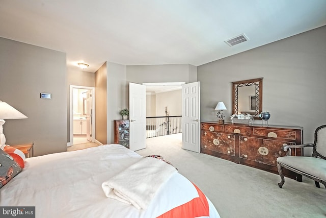 bedroom featuring light carpet and ensuite bath