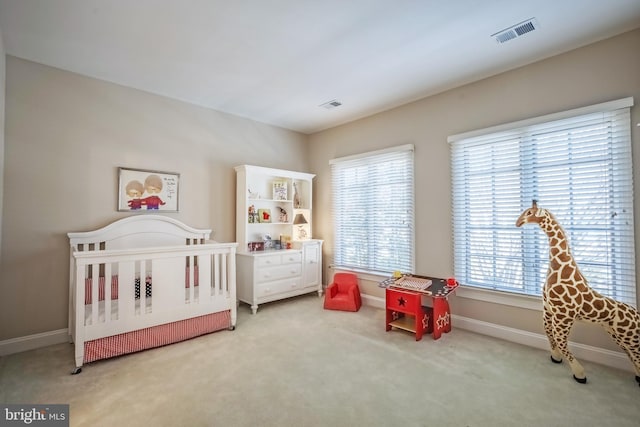 bedroom featuring a nursery area and carpet flooring