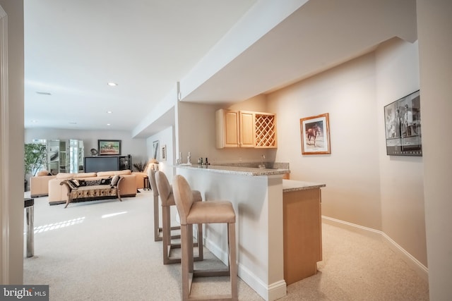 bar featuring light carpet and light brown cabinetry