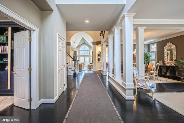 hallway with dark wood-type flooring, ornamental molding, a wealth of natural light, and ornate columns