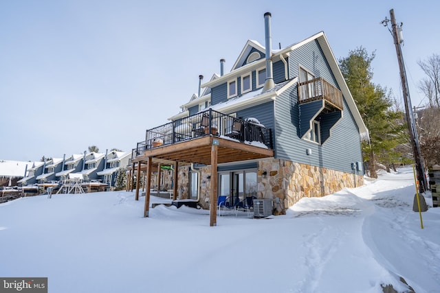 snow covered property featuring a wooden deck and central AC