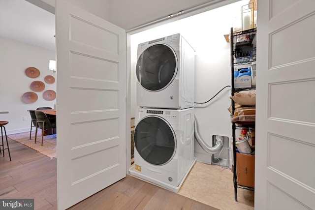 laundry area featuring stacked washing maching and dryer and light wood-type flooring