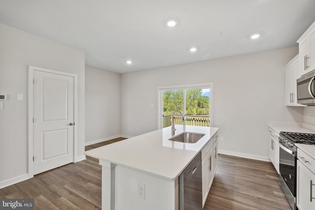 kitchen featuring hardwood / wood-style floors, sink, white cabinetry, appliances with stainless steel finishes, and an island with sink