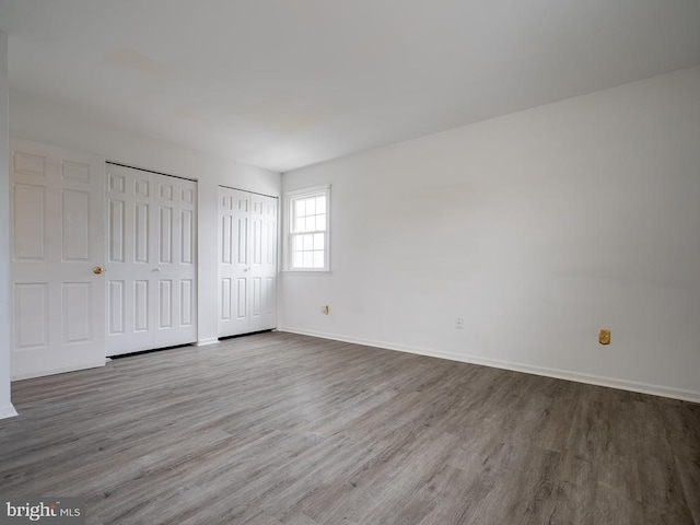 unfurnished bedroom with light wood-type flooring and two closets