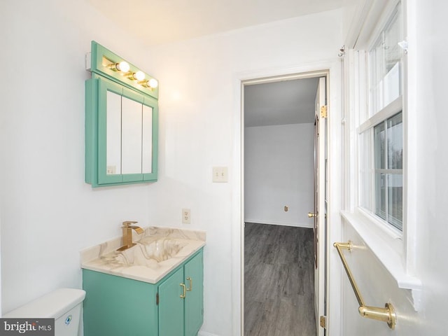 bathroom featuring toilet, vanity, a healthy amount of sunlight, and hardwood / wood-style flooring