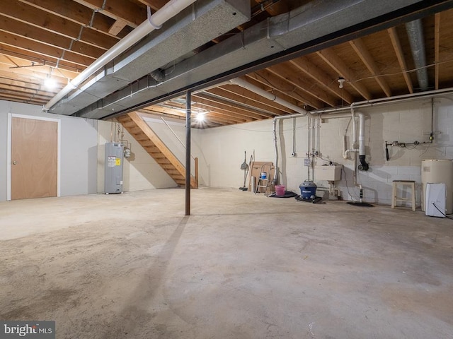 basement featuring water heater, electric water heater, and sink