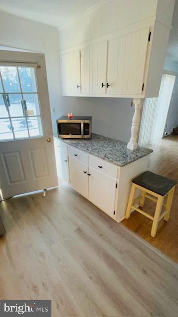 kitchen with light stone counters, light hardwood / wood-style floors, and white cabinets