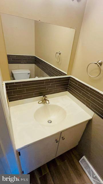 bathroom featuring toilet, vanity, and backsplash