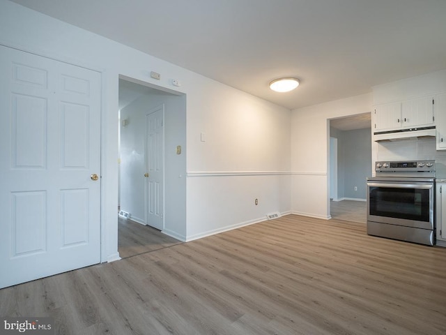 kitchen with stainless steel electric stove, white cabinetry, and light hardwood / wood-style flooring