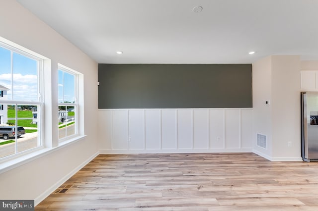 spare room with a wealth of natural light and light hardwood / wood-style flooring