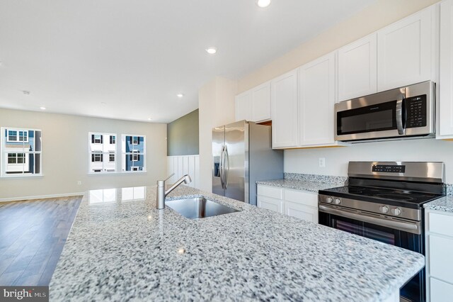 kitchen with light stone countertops, sink, white cabinetry, and stainless steel appliances