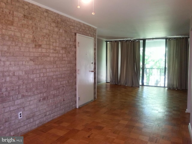 unfurnished room with parquet flooring, brick wall, and crown molding