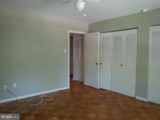 unfurnished bedroom with ceiling fan and dark parquet flooring