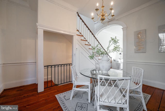 dining space featuring baseboards, wood-type flooring, stairway, an inviting chandelier, and crown molding