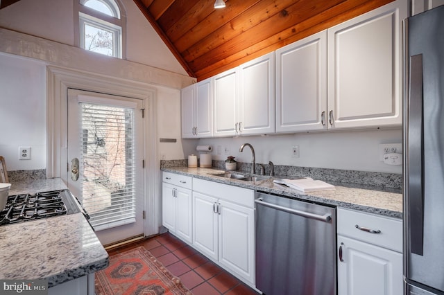 kitchen with stainless steel appliances, white cabinetry, a sink, and dark tile patterned floors