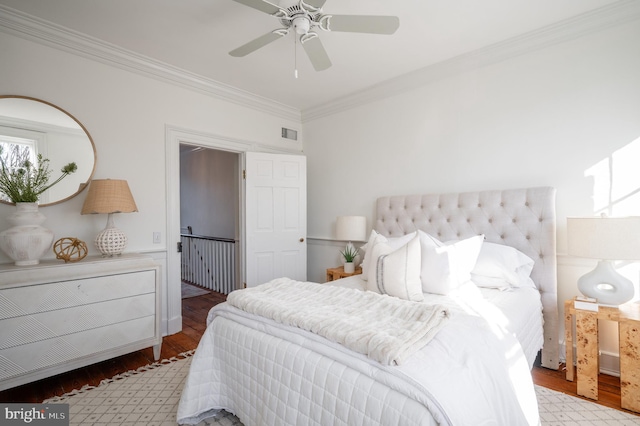 bedroom with a ceiling fan, visible vents, crown molding, and wood finished floors