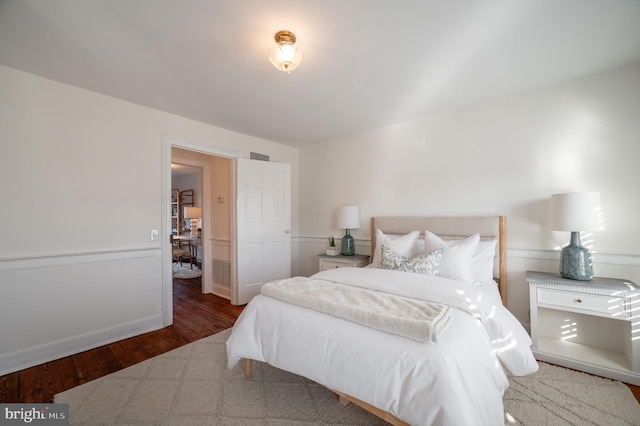 bedroom featuring wood-type flooring and wainscoting