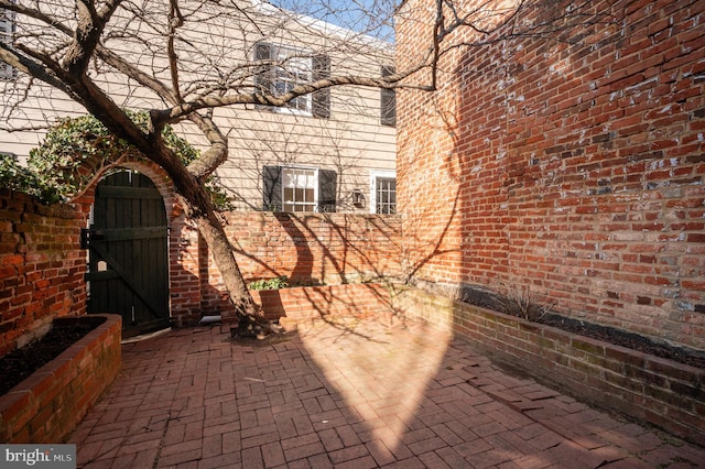 exterior space featuring a gate, a patio, and brick siding