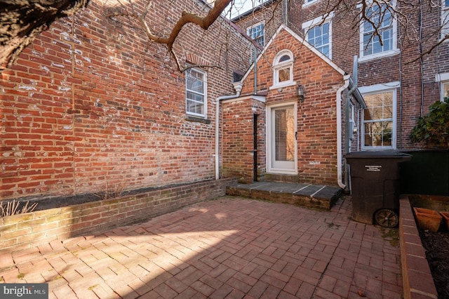 view of exterior entry with brick siding and a patio